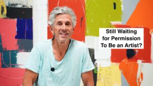 Portrait of a smiling older man in a light blue shirt in front of a bold, colorful abstract mural with the text 'Still Waiting for Permission To Be an Artist?'
