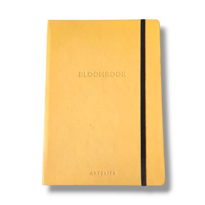 Yellow hardcover notebook with a black elastic strap running along the right edge, embossed with BLOOMBOOK on the cover.