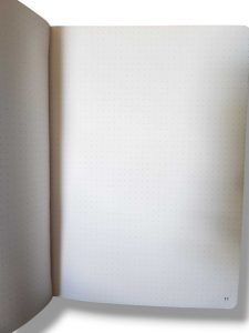 Open notebook with dotted pages, left page curved; page number 11 visible at bottom right.