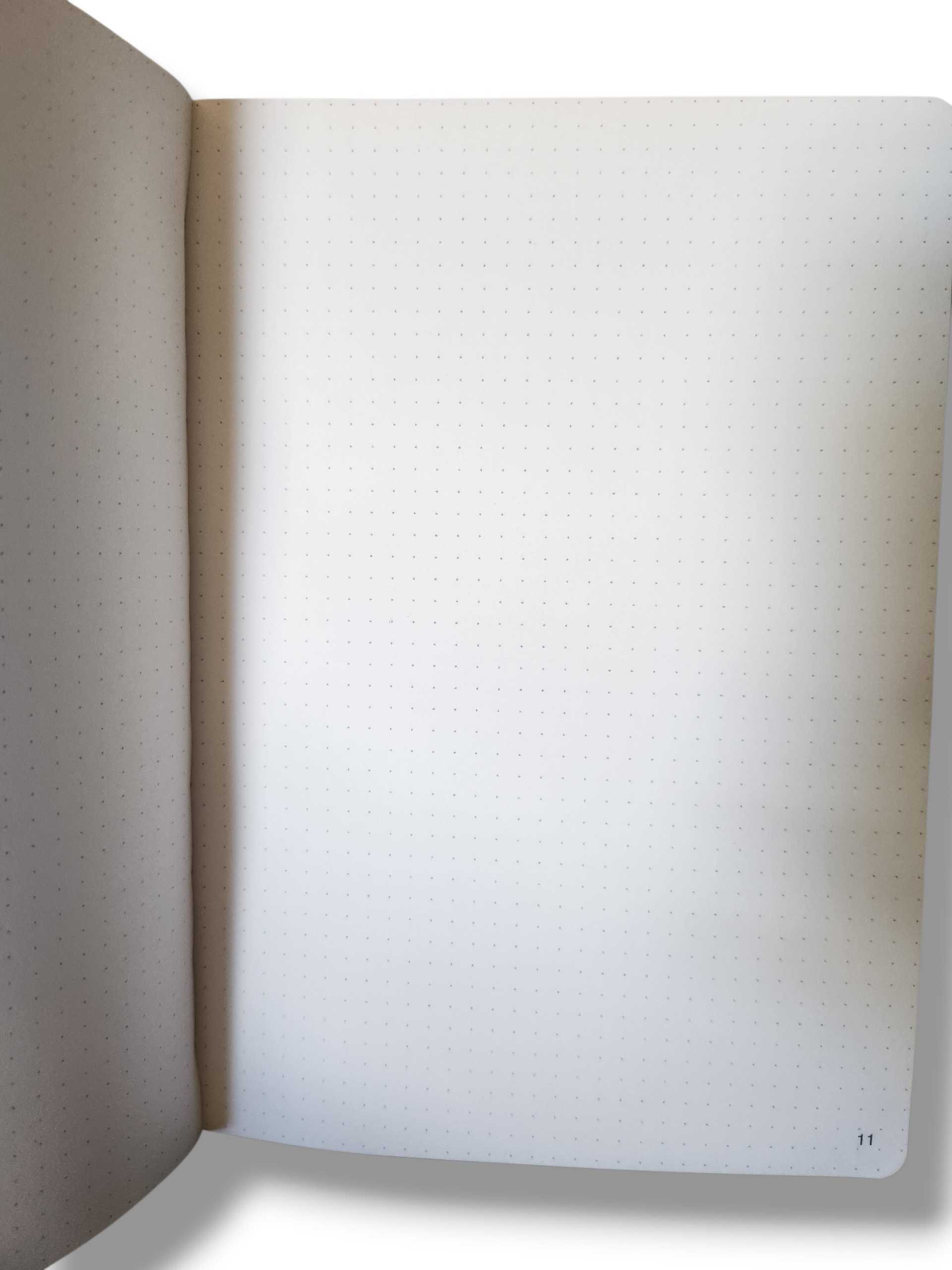 Open notebook with dotted pages, left page curved; page number 11 visible at bottom right.