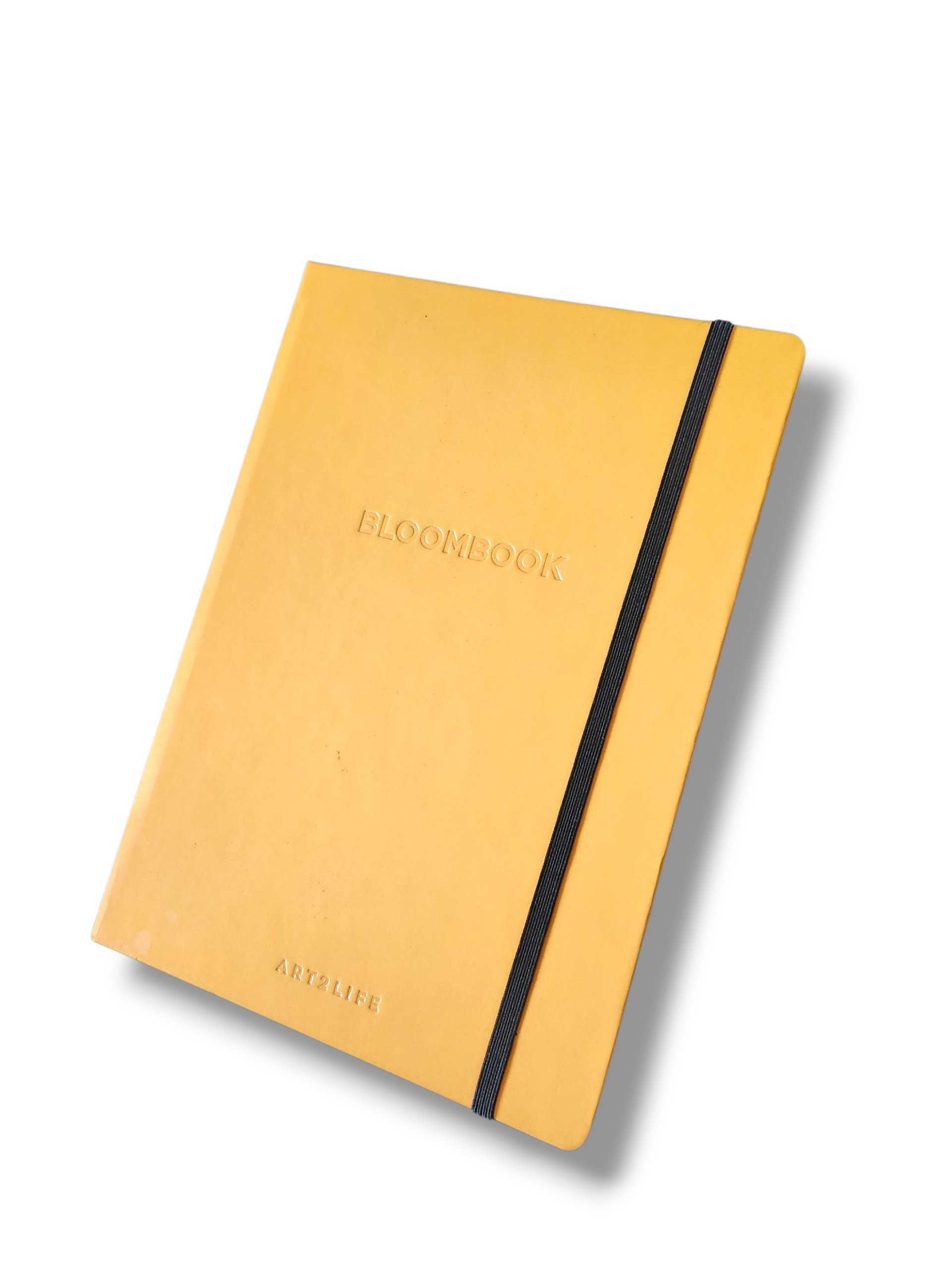 Yellow notebook with a black elastic strap running vertically along the right edge, viewed at an angle.