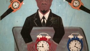 A man in a suit holds two alarm clocks (red and blue) in a suitcase, symbolizing time management.